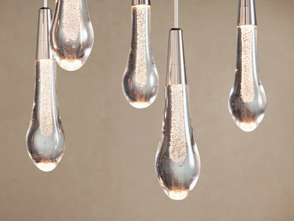 Soltaire Linear Chandelier: multiple teardrop clear glass lights with internal bubbles & silver caps, hanging at varying lengths.