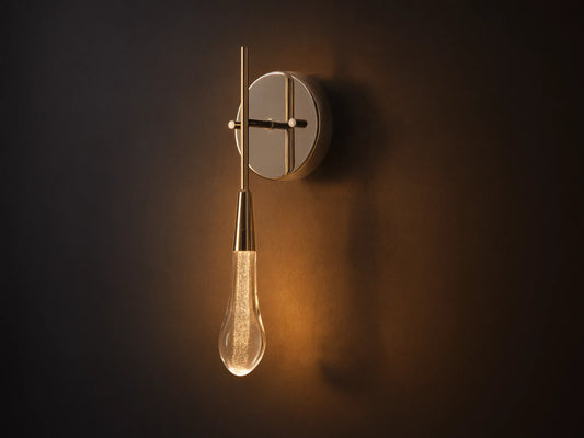 Soltaire Sconce with a shiny nickel backplate, featuring a glowing, clear tear-drop glass light fixture with internal bubbles.