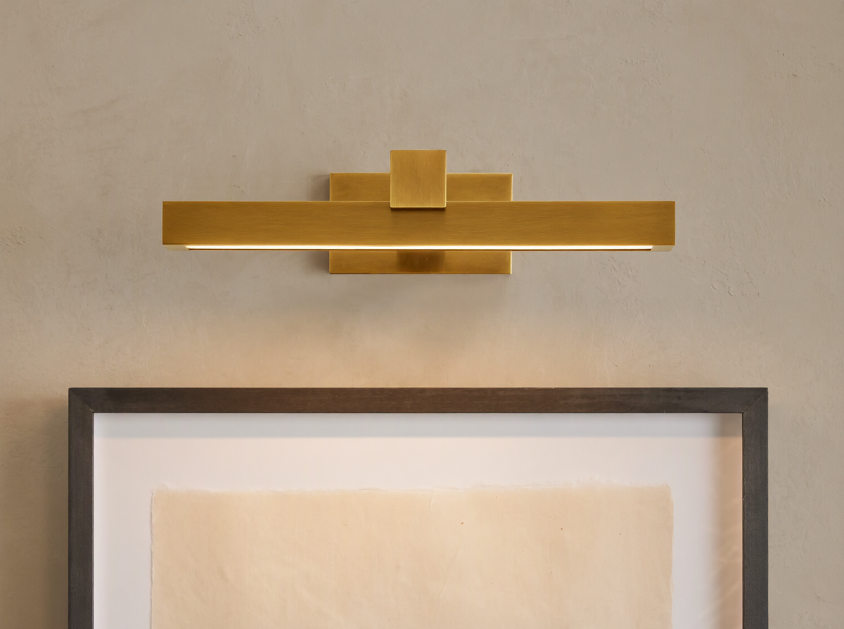 Corinth Picture Light Sconce, brass rectangular bar with LED light, mounted on wall above framed art.