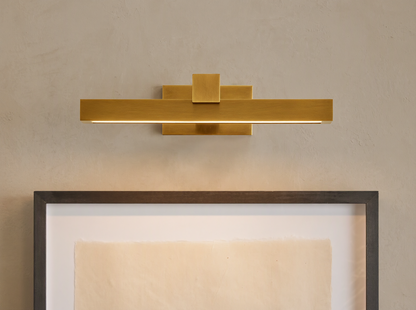 Corinth Picture Light Sconce, brass rectangular bar with LED light, mounted on wall above framed art.