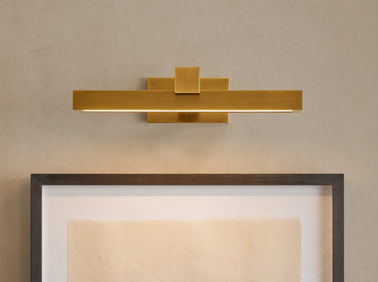 Corinth Picture Light Sconce, brass rectangular bar with LED light, mounted on wall above framed art.