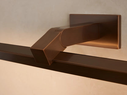 Corinth Picture Light Sconce: a bronze rectangular bar light mounted on a beige wall, positioned above a framed abstract artwork.