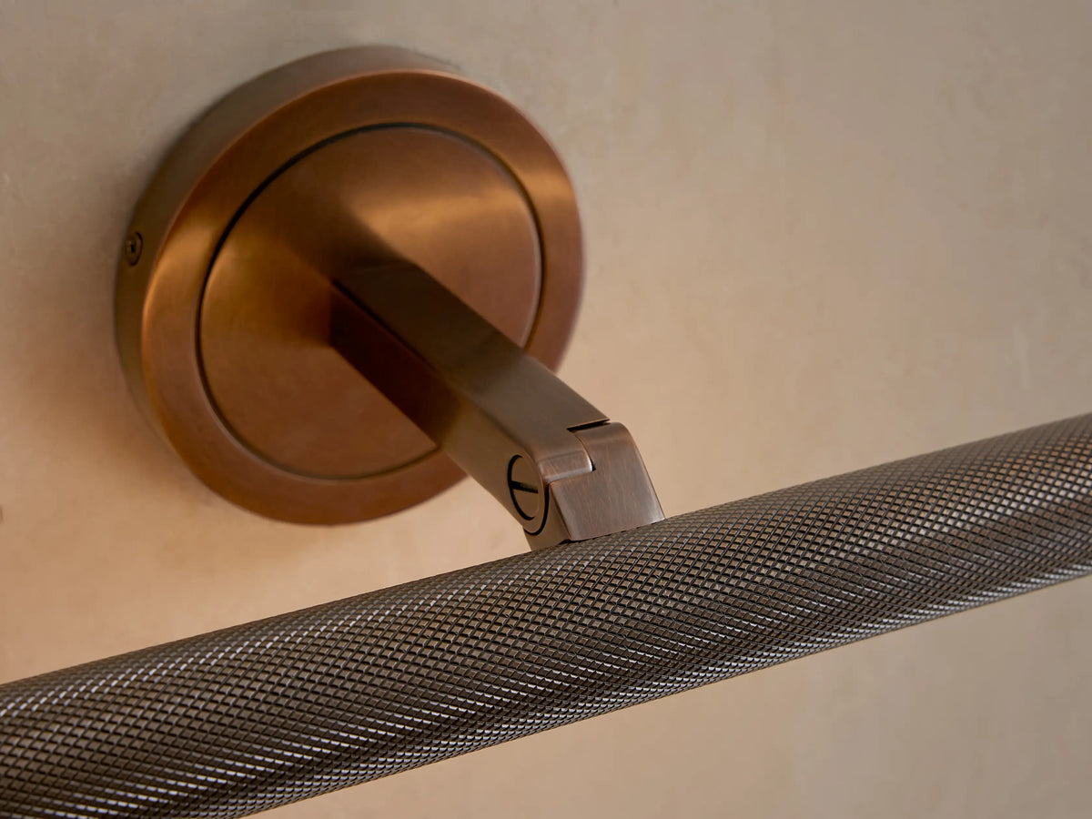 Close-up of antique brass Monroe Picture Light Sconce, showing round base, angled arm, and knurled horizontal bar.