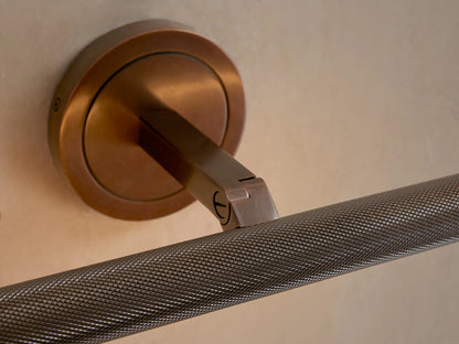 Close-up of antique brass Monroe Picture Light Sconce, showing round base, angled arm, and knurled horizontal bar.