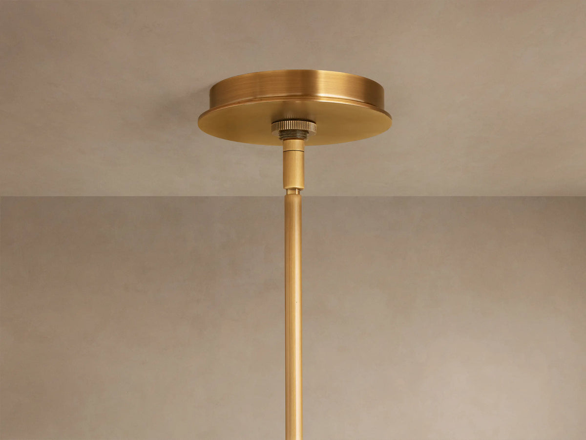 Close-up of Daphne Metal Round Chandelier with antique brass finish. Two shades emit warm light, suspended by rods against a muted wall.