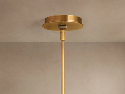 Close-up of Daphne Metal Round Chandelier with antique brass finish. Two shades emit warm light, suspended by rods against a muted wall.