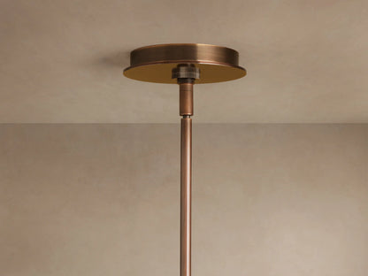 Close-up of Daphne Metal Round Chandelier with bronze finish. Two cylindrical shades illuminate warm light; a larger round shade glows above.