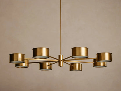 Daphne Metal Round Chandelier in gold/brass with eight drum-shaped shades emitting warm light, hanging from a central rod.