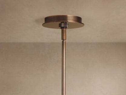 Daphne Metal Round Chandelier, close-up of warm bronze finish, cylindrical metal shades casting a soft, warm glow.