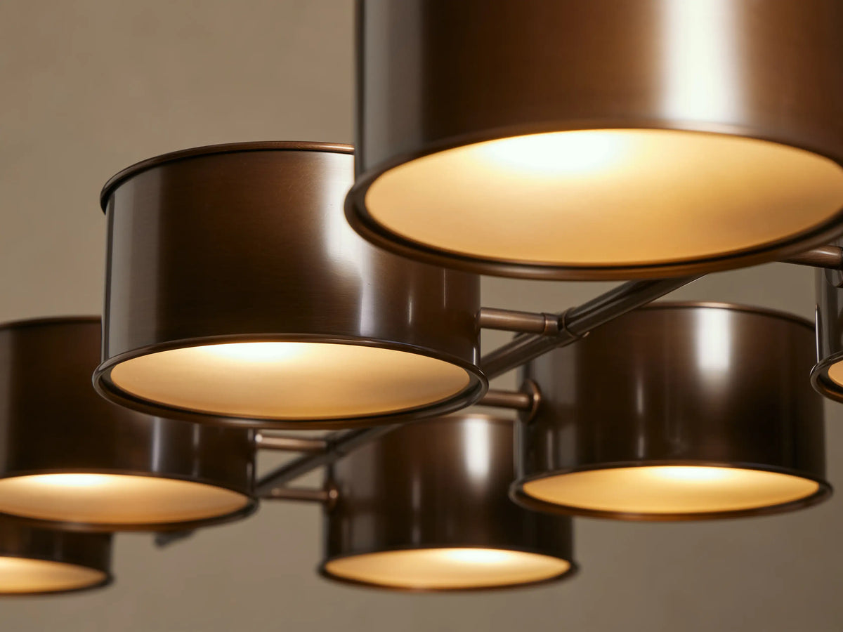 Close-up of Daphne Metal Linear Chandelier with warm bronze shades. One shade is angled, showing a frosted diffuser with a warm glowing light.
