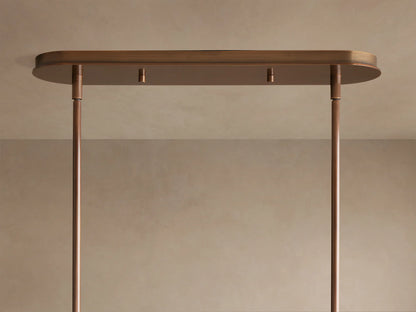 Close-up of Daphne Metal Linear Chandelier with multiple warm bronze metal shades glowing with soft, inviting light.