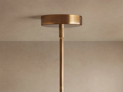 Christie Pendant: Close-up of beige striated natural stone, brass collar, and glowing milk glass shade hanging.