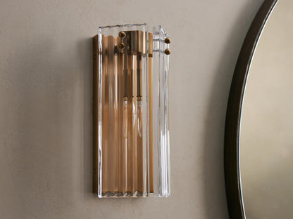 Delsie Sconce: Rectangular wall-mounted light with fluted clear glass and burnished brass frame, casting warm glow.