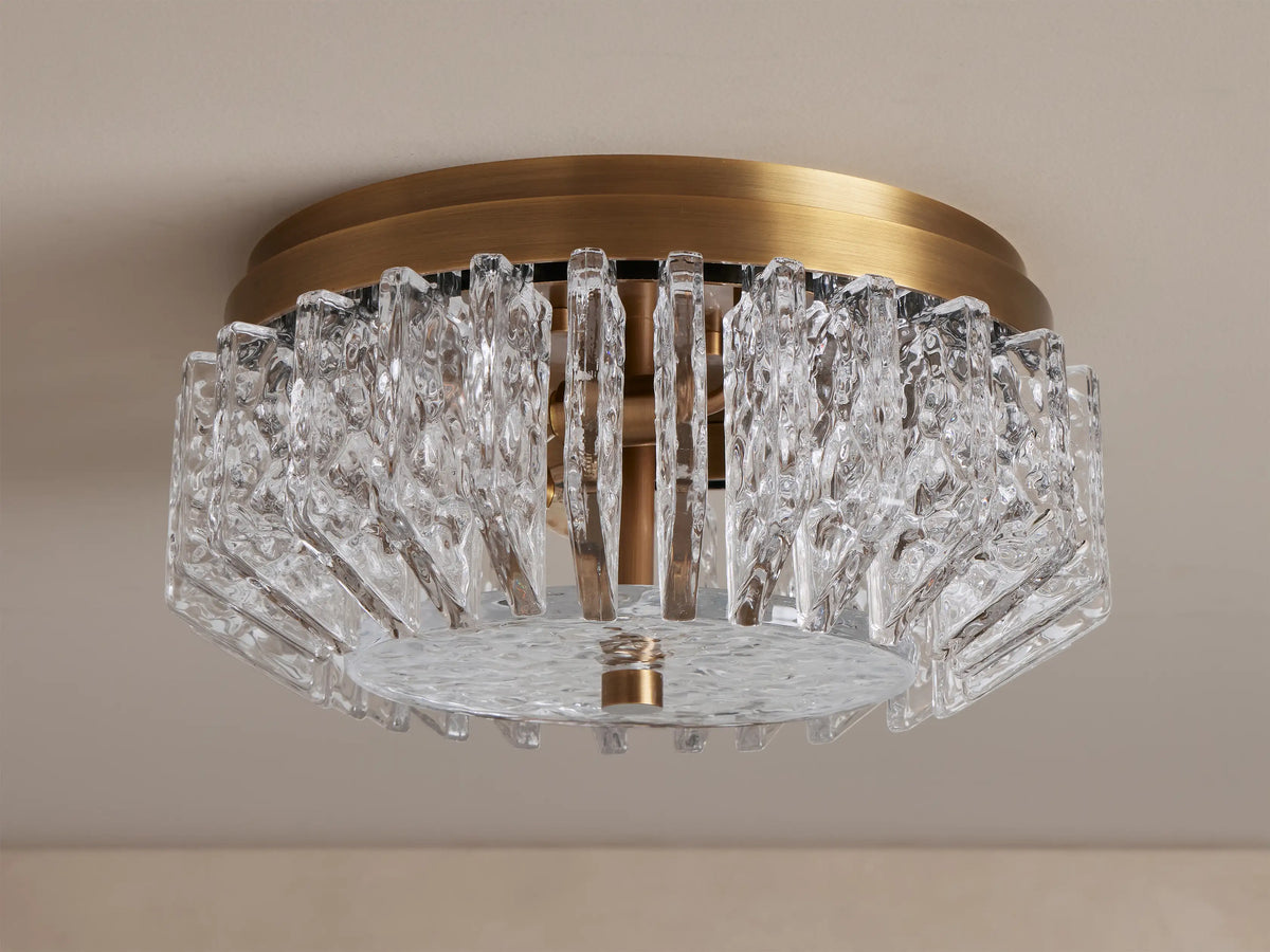 Liliana Flush Mount, a brass ceiling light with intricate, textured clear glass panels glowing softly, seen from below.