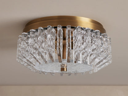Liliana Flush Mount, a brass ceiling light with intricate, textured clear glass panels glowing softly, seen from below.