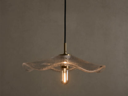 Front view of a clear wavy glass pendant light with a brass fixture and an exposed filament bulb, hanging from a black cord.