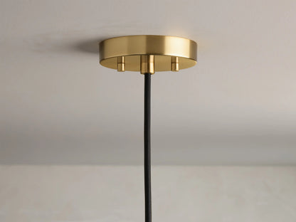 Close-up of the round, brushed brass ceiling canopy with three visible gold screws and a black braided cord.