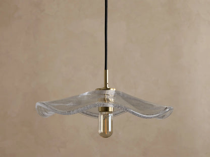 Front view of a clear wavy glass pendant light with a brass fixture and an exposed filament bulb, hanging from a black cord.