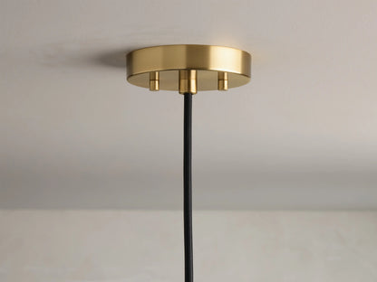 Close-up of a wavy, clear bubbled glass light shade with a warm glowing Edison bulb and a brass fixture.