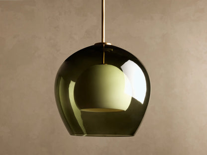 Romy Pendant featuring a dark green smoked glass outer dome and a light green inner shade, hanging from a brass rod.