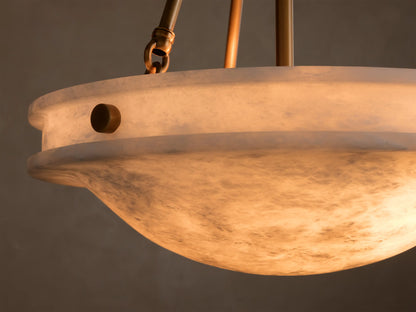 Close-up of the alabaster Edith Pendant's shade, glowing warmly, revealing natural marbling and a round brass button detail.