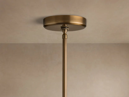 Close-up of the brass finish ceiling canopy and suspension rod of the Edith Pendant attached to a beige ceiling.