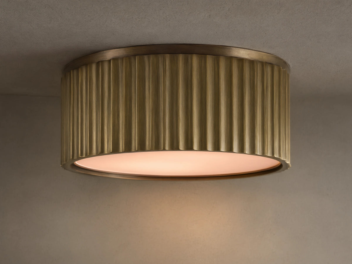 Upward view of a glowing brass ribbed flush mount ceiling light fixture against a white ceiling.
