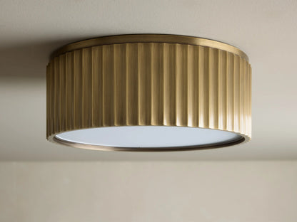 Upward view of a glowing brass ribbed flush mount ceiling light fixture against a white ceiling.