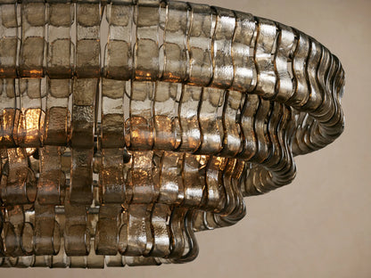 Ghiaccio Round Chandelier, close-up. Textured smoky grey curved glass segments glow with warm light from within.