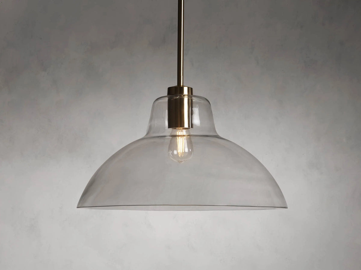 Bauer Dome Pendant with a clear glass dome and brass hardware, suspended from a rod and showing a visible bulb.