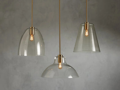Bauer Dome Pendant features a brass-finished steel fixture with a clear glass dome, housing an LED bulb, against a neutral background.