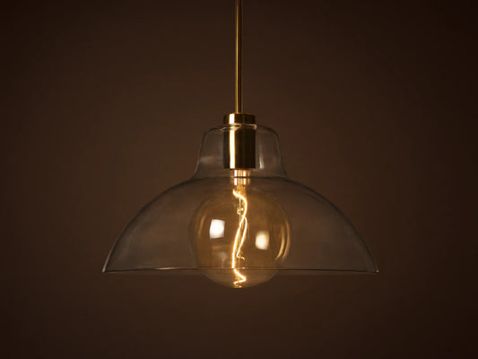 Bauer Dome Pendant with a transparent glass shade showcasing a glowing LED G200 bulb and brass finish, suspended by a rod.