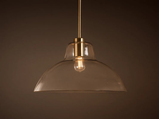 Bauer Dome Pendant with a clear glass dome and brass hardware, suspended from a rod and showing a visible bulb.