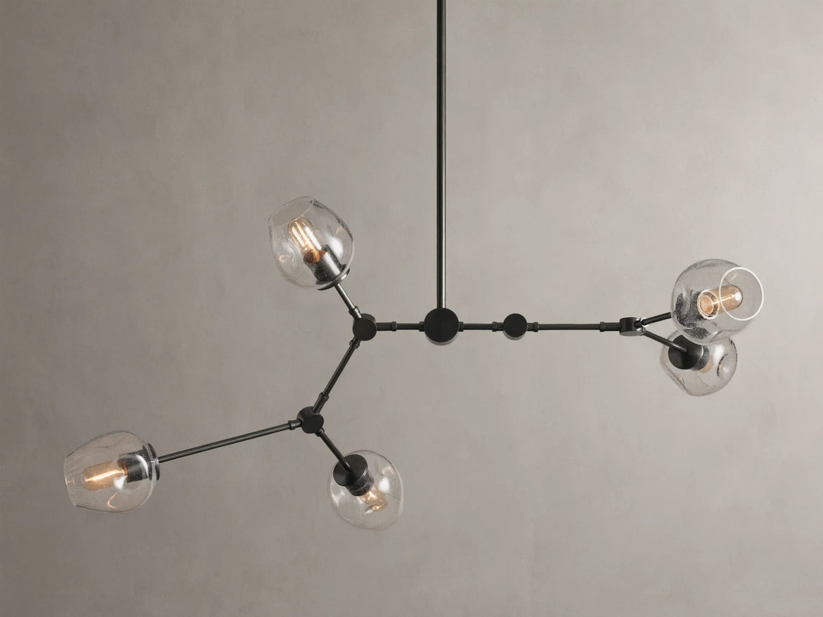 Noella Bronze Chandelier with five arms, clear glass bulb covers, and a sleek bronze finish against a light gray background.