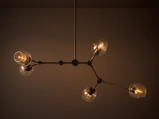 Noella Bronze Chandelier with five arms, clear glass bulb covers, and a sleek bronze finish against a light gray background.