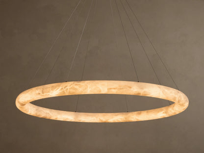 Front view of an illuminated Alabaster Ring Pendant Light, glowing warm white, revealing creamy translucent material with swirling veins.