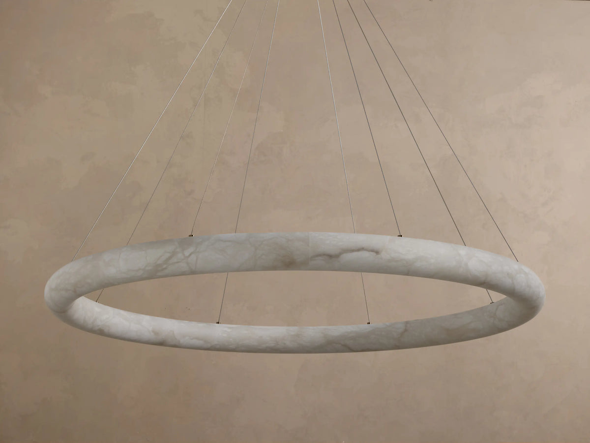 Front view of an illuminated Alabaster Ring Pendant Light, glowing warm white, revealing creamy translucent material with swirling veins.