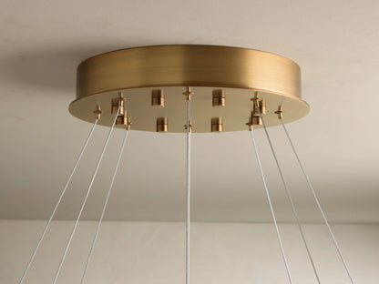 Close-up of ring pendant light with warm glowing, veined alabaster diffuser and bronze-toned metal frame, suspended by wires.