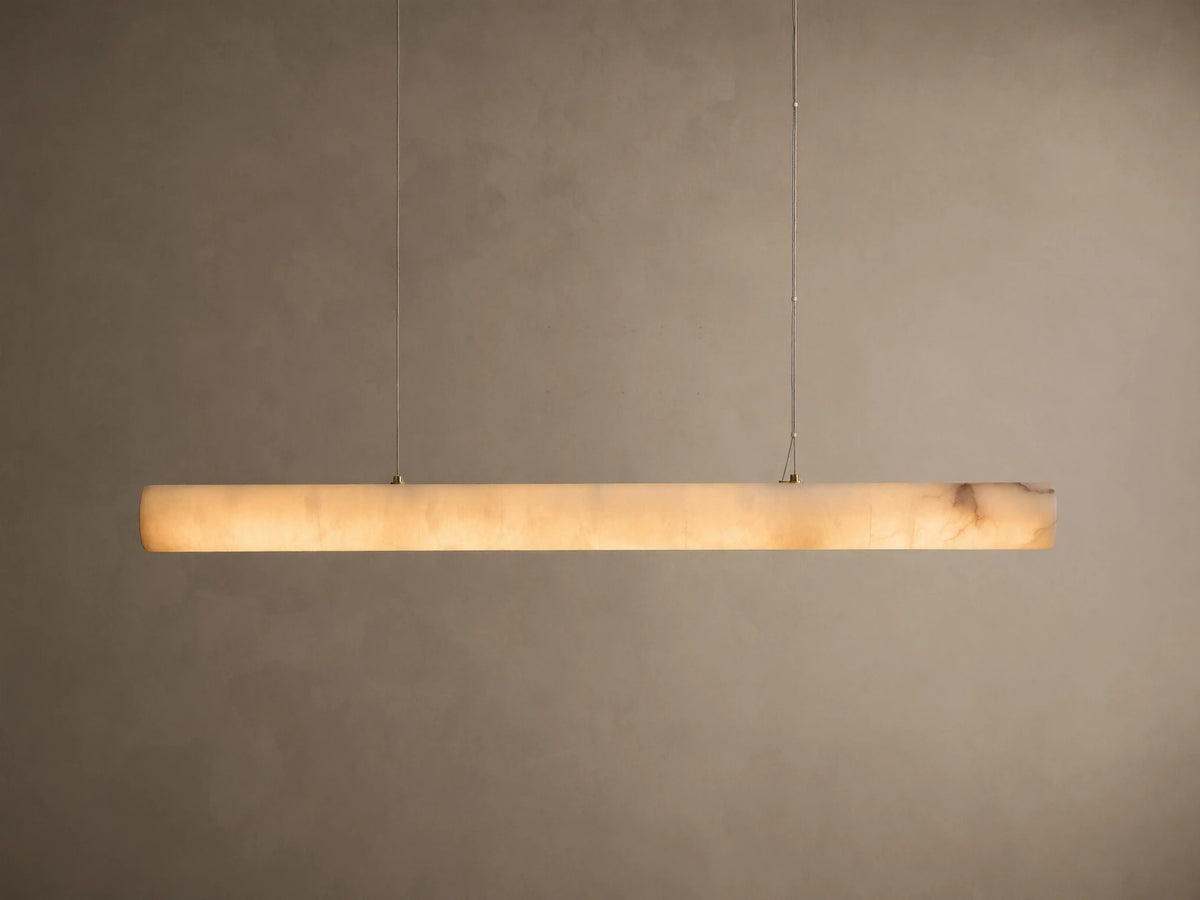 Translucent off-white onyx linear pendant light, glowing warmly with visible brown veining, suspended by thin wires.