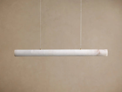 Translucent off-white onyx linear pendant light, glowing warmly with visible brown veining, suspended by thin wires.