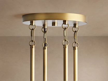 Andreas Round Chandelier, brass, with glowing filament bulbs visible in clear fluted glass cylinders.