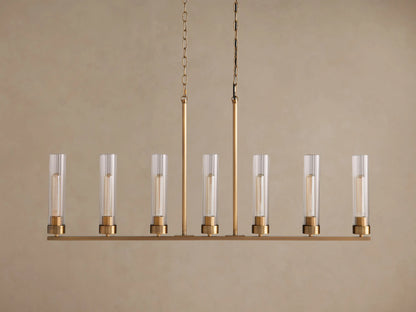 Andreas Linear Chandelier: Plated brass finish, 7 clear ribbed glass shades with visible filament bulbs, hanging from two chains.