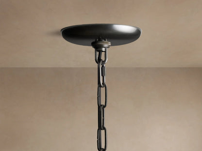Close-up of the Ghiaccio Round Chandelier's dark metal canopy & chain, attached to a light beige ceiling.