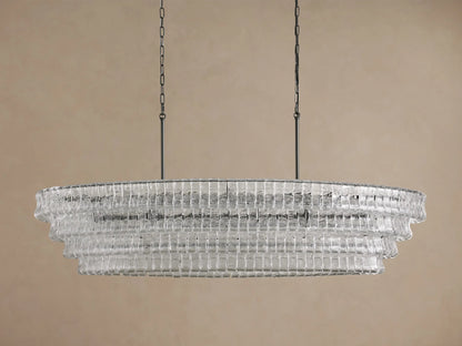 Illuminated Ghiaccio Oval Chandelier with layered, ribbed clear glass, suspended by dark chains against a neutral background.