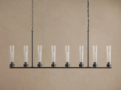 Andreas Linear Chandelier with 8 clear fluted glass shades, dark bronze frame, and warm glowing filament bulbs, hanging from chains.