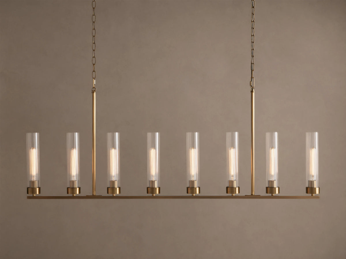 Andreas Linear Chandelier: 8-light, brass-finished, horizontal bar with clear cylindrical glass shades, exposing filament bulbs, hanging.