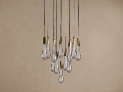 Soltaire Round Chandelier with multiple clear, textured teardrop glass pendants, each with a brass cap, hanging at varying lengths.