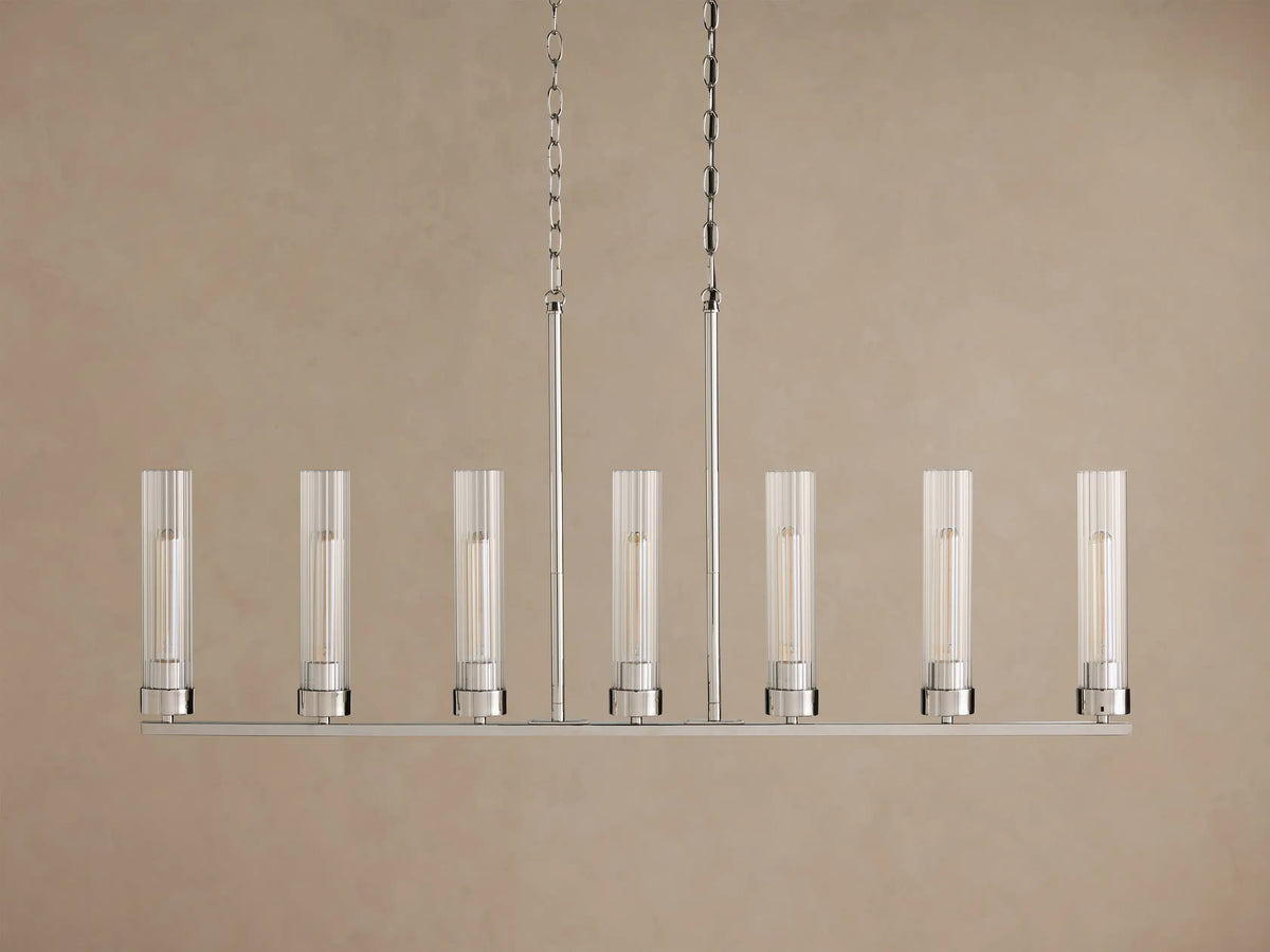 Andreas Linear Chandelier with 7 illuminated bulbs in fluted glass cylinders on a polished silver frame, suspended by chains.