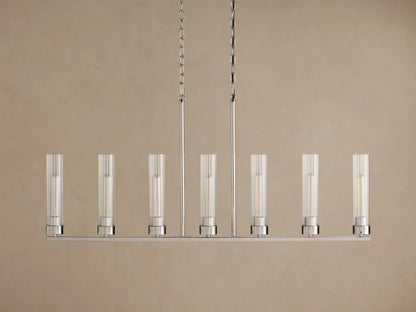 Andreas Linear Chandelier with 7 illuminated bulbs in fluted glass cylinders on a polished silver frame, suspended by chains.