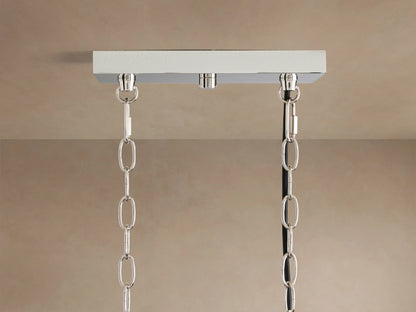 Close-up of Andreas Linear Chandelier: horizontal plated brass bar, five illuminated fluted glass cylinders with warm bulbs.